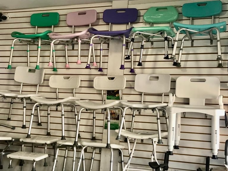 Display of shower chairs in various colors mounted on a wall-mounted pegboard system at a retail store