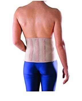 Man wearing a beige medical back support brace with blue athletic shorts, shown from behind
